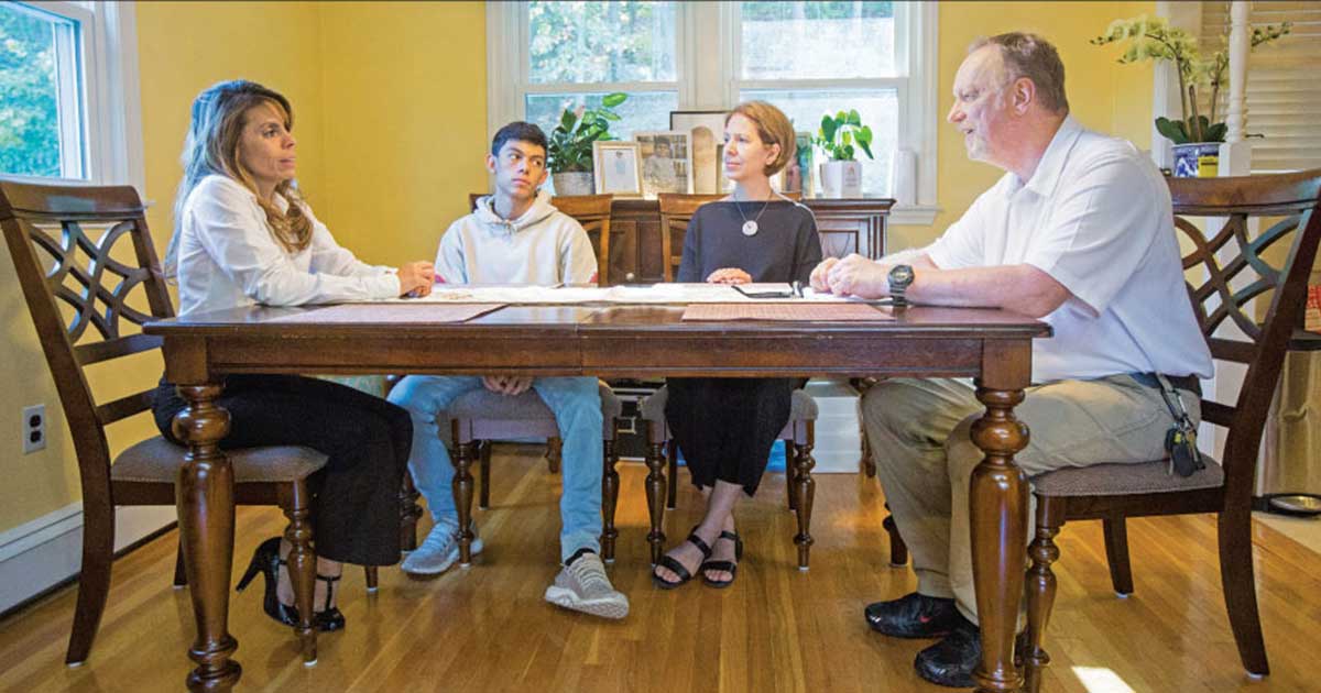 Mary Jo Rendón and Victor Vaitkunas of Waltham High School met with junior Michael DeGloria and his mother, Johana Rodríguez, left, during a recent home visit. Vaitkunas, an electrical technology teacher, said his own positive experiences in school made him want to "make a difference in kids’ lives."